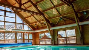 A large indoor swimming pool with a high ceiling and large windows.
