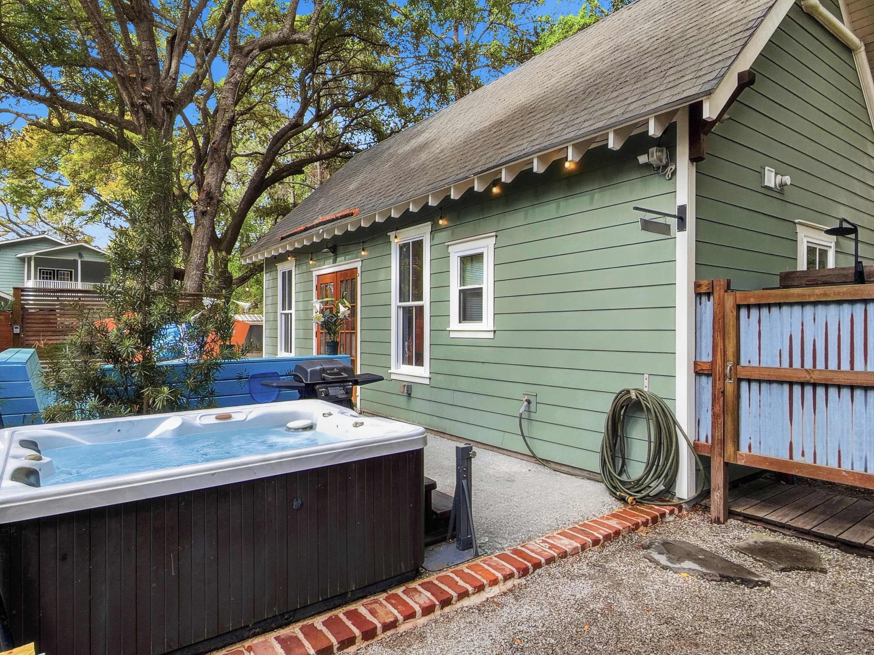 A house with a hot tub, a wooden deck, and a fenced yard.