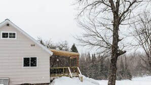 A snow-covered house with a wooden deck and a large tree in the background. - Rental gateway in UP (Nisula)