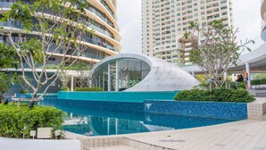 Un edificio moderno con fachada de vidrio curva y una piscina frente a él.