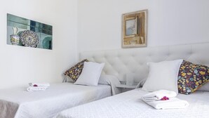 Een hotelkamer met twee bedden, witte beddengoed en een decoratieve spiegel.