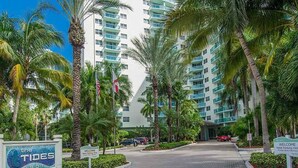 A hotel entrance with palm trees, a sign reading 'Welcome,' and a building with multiple balconies. - Oceanfront, heated pool & Sea Breeze balcony (Hollywood)