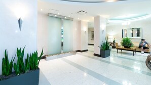 A modern lobby with a reception desk, seating area, and potted plants. - Oceanfront, heated pool & Sea Breeze balcony (Hollywood)