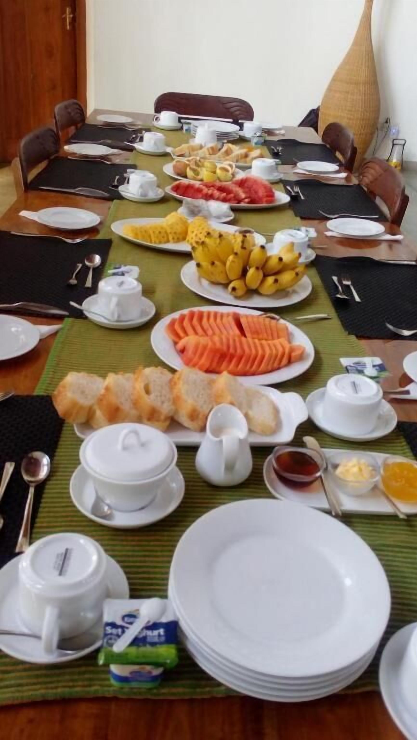 A conference table set with various food items, plates, and utensils, indicating a meal or buffet setup.