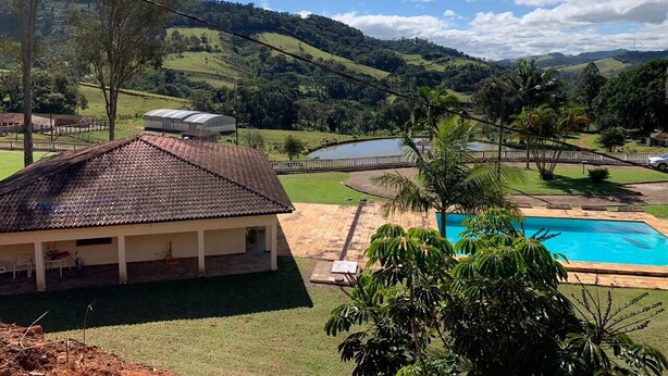 Ein Haus mit Ziegeldach, Schwimmbad und Blick auf grüne Hügel und einen See.