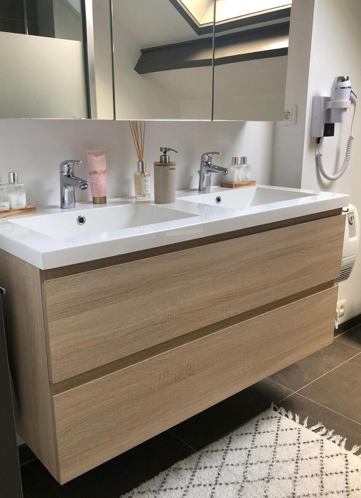 A modern bathroom with a double sink vanity, a mirror, and a telephone.