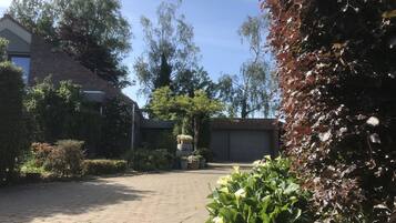 A paved courtyard with a brick building, a garage, and various plants and trees.