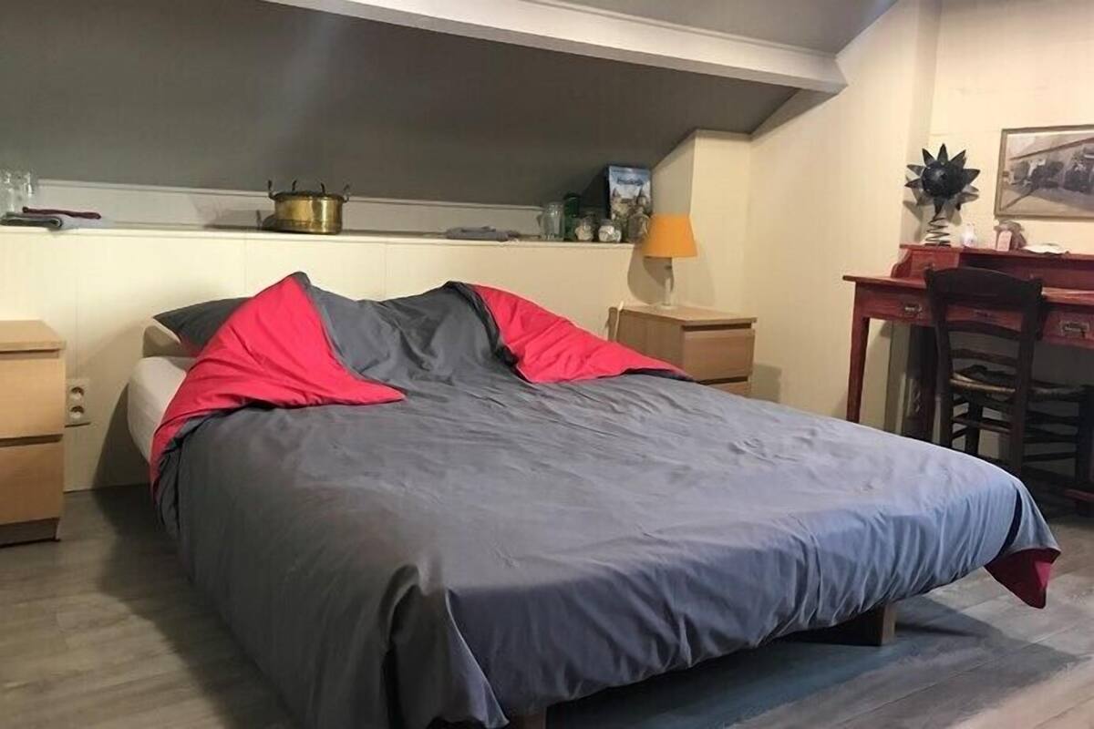 Un dormitorio con cama, mesitas de noche, un escritorio y una silla.