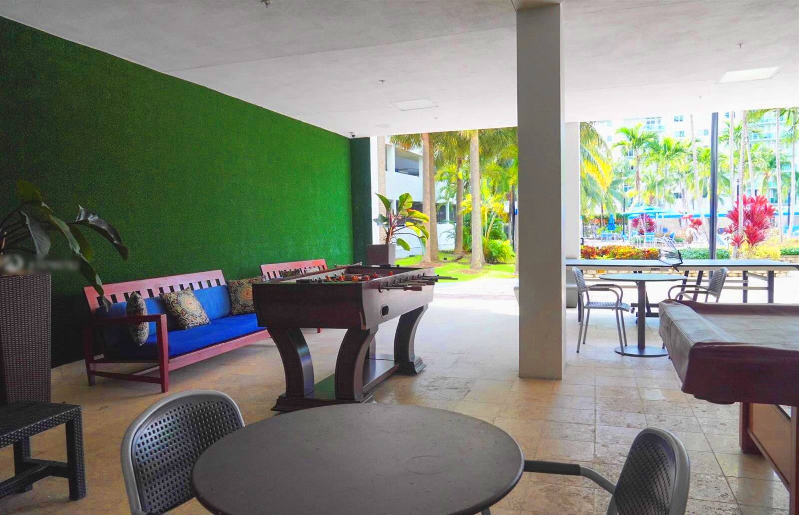 A casual outdoor seating area with a foosball table, a sofa, and a table with chairs.