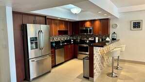 A modern kitchen with stainless steel appliances, wooden cabinets, and a tiled backsplash.
