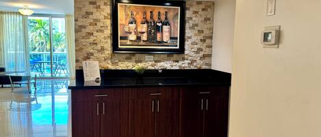 A modern kitchen with dark wooden cabinets, a stone backsplash, and a framed wine bottle display.
