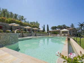 Ein Pool mit Steinwänden und -terrasse, umgeben von Sonnenschirmen und Topfpflanzen.