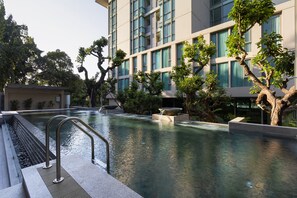 A modern hotel with a swimming pool, surrounded by trees and a multi-story building with large windows. - ANA Park (Chiang Mai)