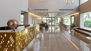 Un vestíbulo amplio con mostrador de recepción, zona de estar y grandes ventanales con vistas al exterior.