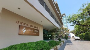 Entrada de un edificio con un letrero que dice "ANA PARK CHIANGMAI" y un camino que conduce a la entrada.