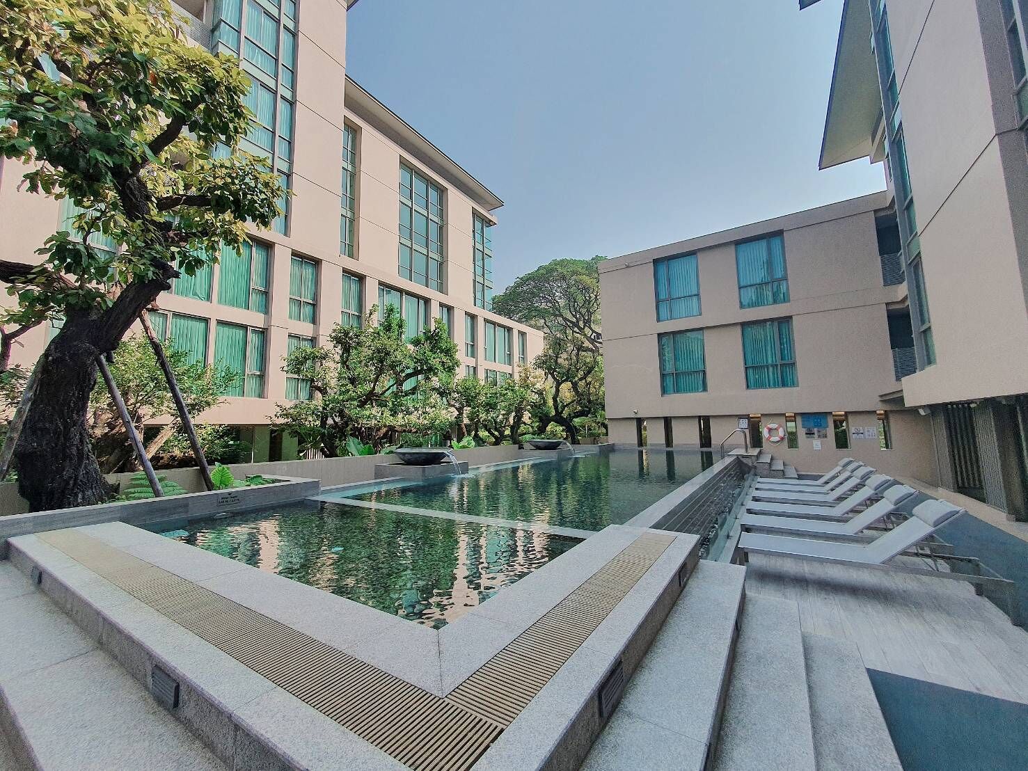 Un edificio moderno con una piscina rectangular y escalones que bajan a ella.