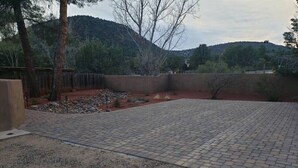 A paved patio area with a gravel path leading to a wooden fence. - Robin`s Red Rock Getaway Suite A (Sedona)