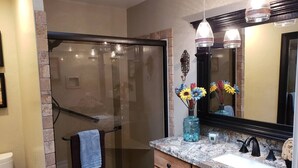 A bathroom with a glass shower enclosure, a vanity with a marble countertop, and a large mirror. - Robin`s Red Rock Getaway Suite A (Sedona)