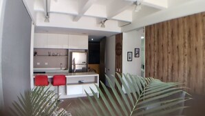 Una cocina moderna con armarios blancos, una silla roja y un panel de madera.