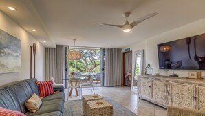 A spacious living area with a sofa, coffee table, and a television. - Dine in paradise on your garden-view lanai (Lahaina)