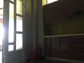 A kitchen with wooden cabinets, a glass-top island, and a red fire extinguisher. - AB Lake Side Ho An Bien (Hai Phong)
