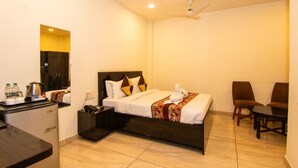 A hotel room with a bed, a desk, a chair, and a small table. - Hotel Vinayak (Haridwar)