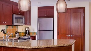 Una cocina con armarios de madera, un refrigerador de acero inoxidable, un microondas y una cafetera.