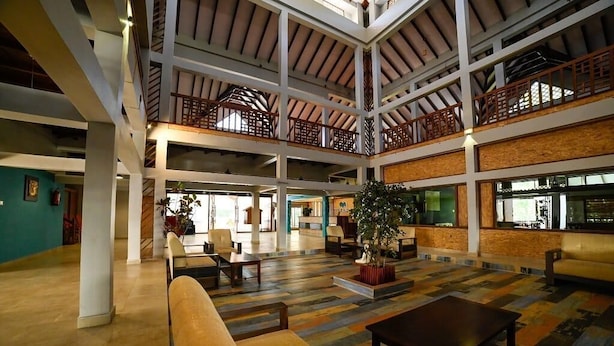 A spacious lobby with a high ceiling, multiple seating areas, and a central plant. - Bowfin Resort (Port Blair)