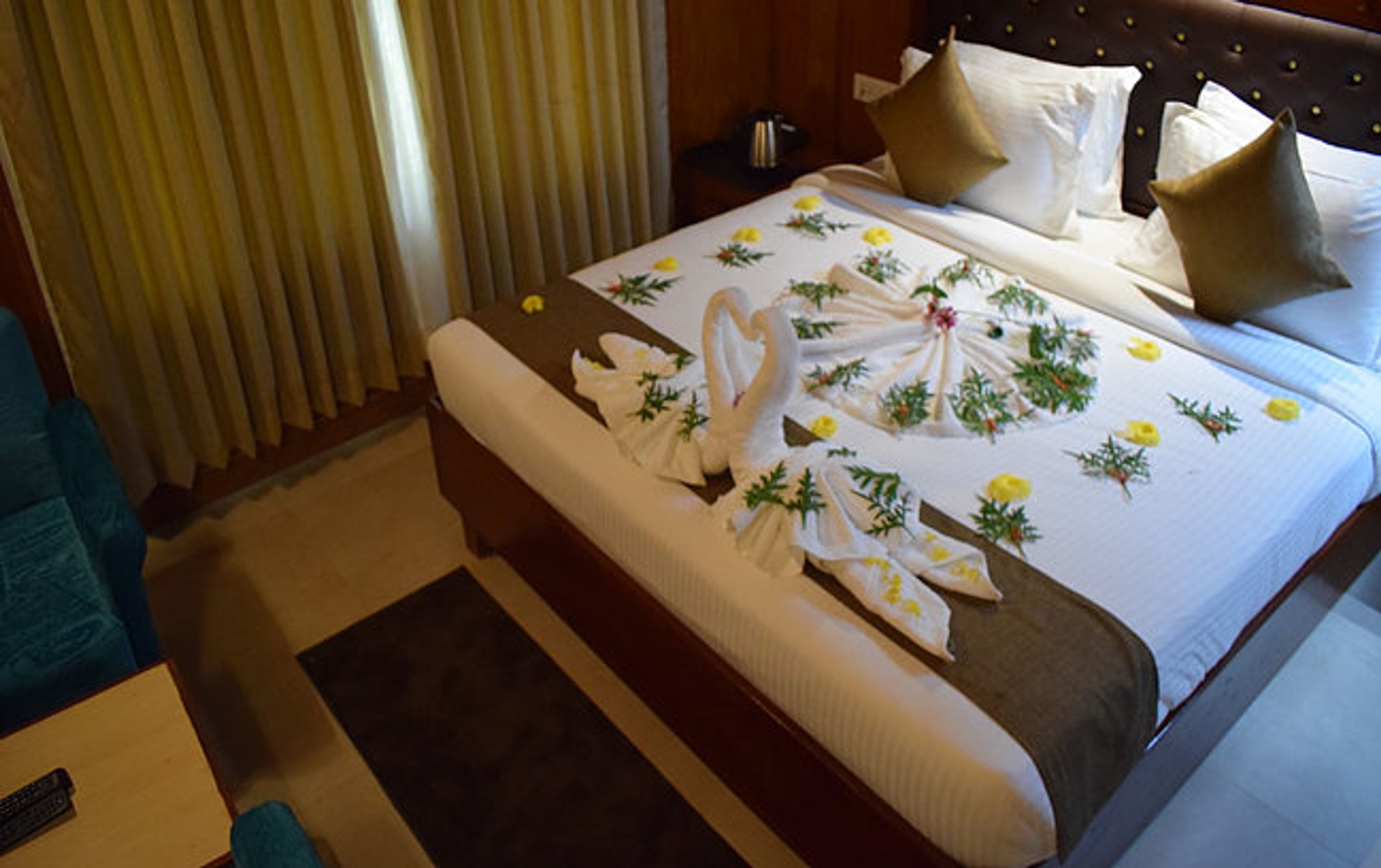 Habitación de hotel con cama, mesita de noche, control remoto y ventana con persianas.