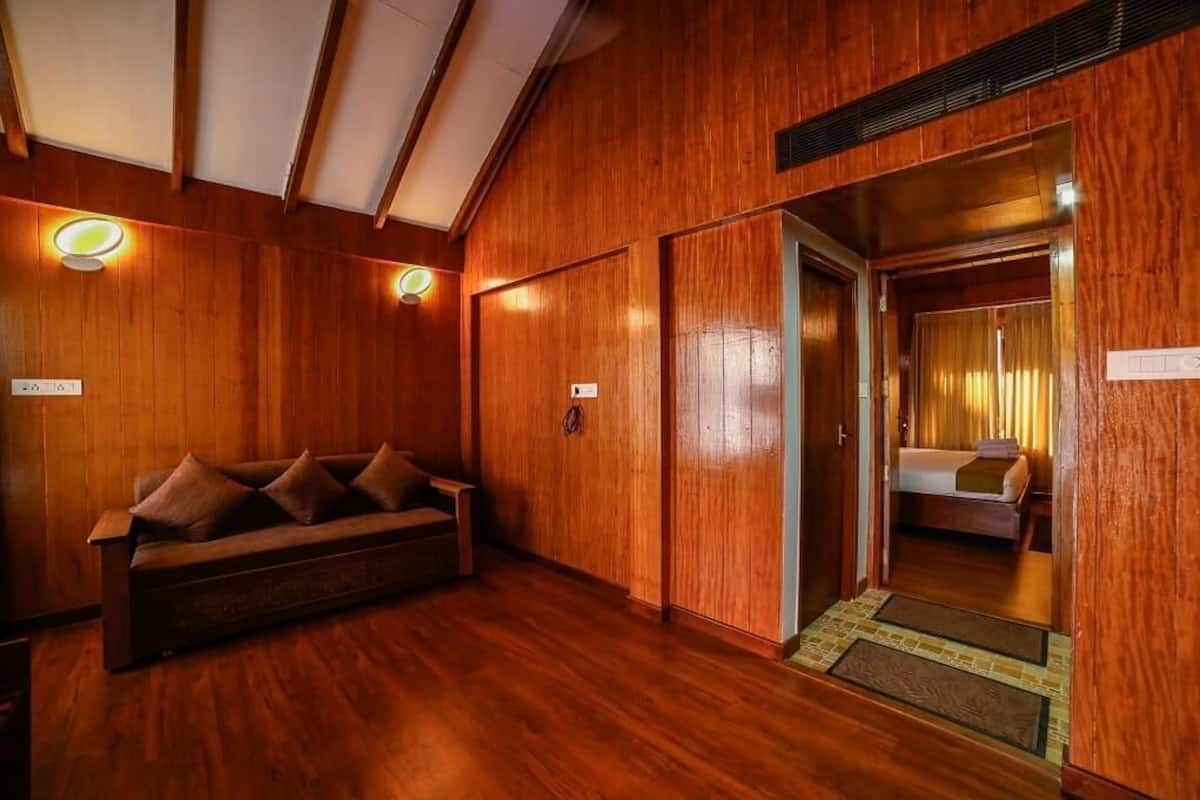 A wooden-floored hallway with a sofa and a bed visible through an open door.