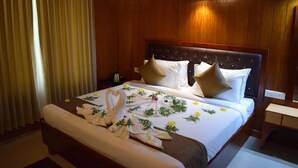 A hotel room with a wooden headboard, a neatly made bed with white linens, and a floral-patterned bedspread. - Bowfin Resort (Port Blair)