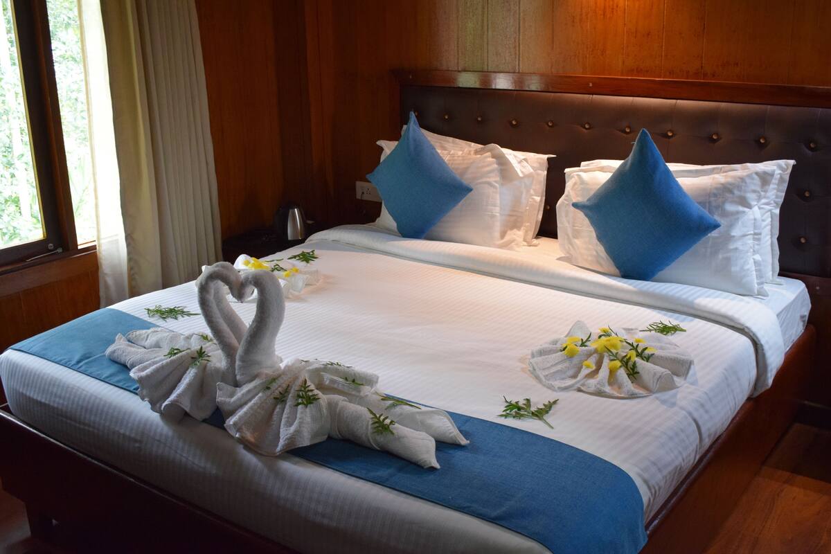 A neatly made bed with white linens, blue pillows, and decorative swan-shaped towels.