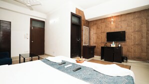 A hotel room with a bed, a desk, a chair, a television, and a wardrobe.