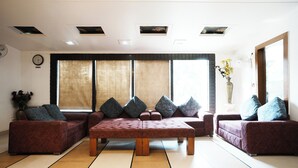 A modern living room with a sectional sofa, a wooden coffee table, and large windows with curtains.