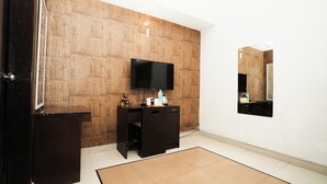 A modern bathroom with a wooden accent wall, a black vanity, a flat-screen TV, and a mirror.