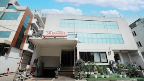 A hotel named "Hotel Om Paradise" with a modern facade, large windows, and a staircase leading to the entrance.
