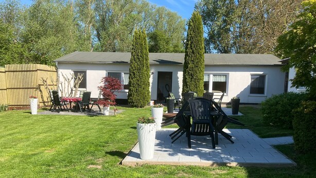A residential backyard with a patio, outdoor furniture, and a tall coniferous tree. - Holiday house No. 5 - Rügen-Fewo 102 (Sagard)
