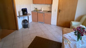 A compact kitchen with wooden cabinets, a coffee maker, and a trash bin. - Holiday house No. 5 - Rügen-Fewo 102 (Sagard)
