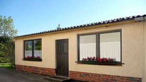 A single-story building with a brick foundation and a beige exterior. - Holiday house No. 5 - Rügen-Fewo 102 (Sagard)