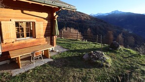 Une cabane en bois dotée d’une terrasse en bois et offrant une vue sur un paysage montagneux.