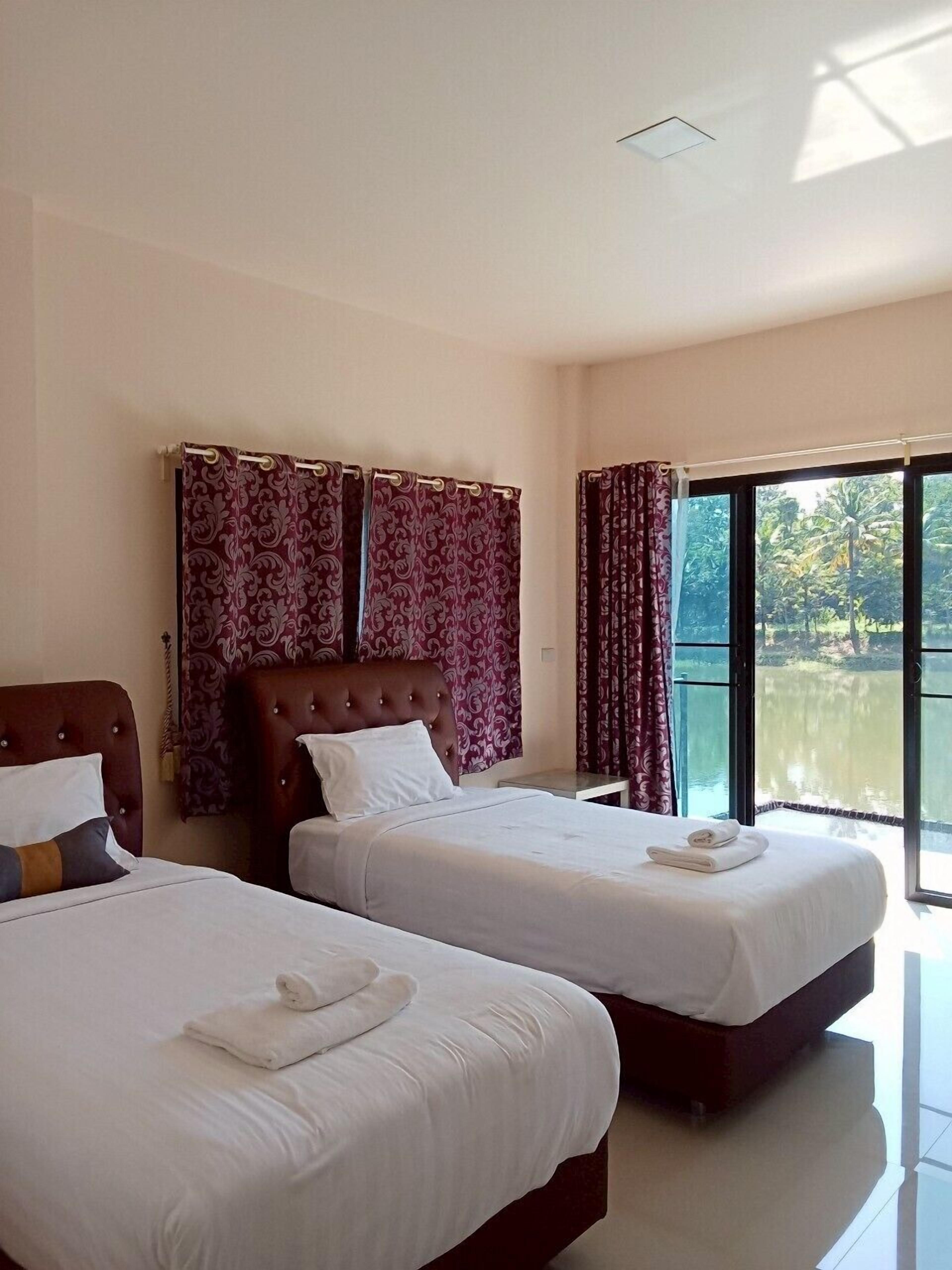 A hotel room with two beds, a large window with a view of a body of water, and a ceiling light.