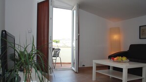 A living room with a white coffee table, a black sofa, a potted plant, and a fruit bowl. - House Ercegovic A2 + 2 (Primošten)
