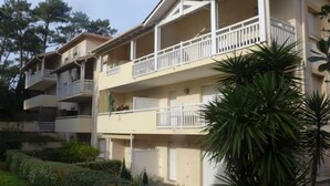 Um edifício residencial com várias andares, varandas, área de jardim e uma palmeira.