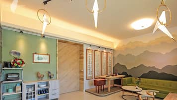 A modern interior with a green sofa, wooden cabinets, and a dining area with a table and chairs.