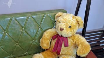 A teddy bear sitting on a green upholstered bench.