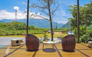 A wooden deck with two wicker chairs, a small round table with cups, and a view of mountains and greenery. - Cloud There House (Ji'an)
