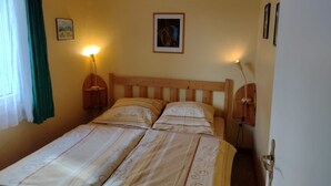 Ein Doppelbett mit Holz Kopfteil, zwei Nachttische mit Lampen, ein gerahmtes Bild an der Wand und eine Tür mit Griff.