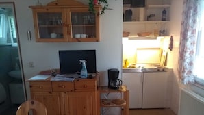 Eine kompakte Küche mit Holzausstattung, einer Kaffeemaschine und einem kleinen Tisch.