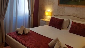 Habitación de hotel con una cama grande, una mesita de noche con una lámpara y un cuadro en la pared.