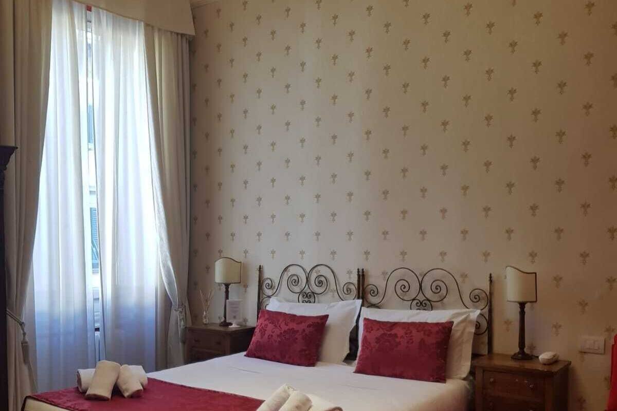 A hotel room with a large bed, two bedside tables, and a window with curtains.